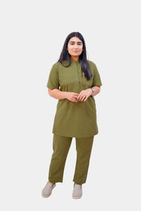 A woman modeling a matching olive green two-piece kurta set against a plain light gray background.